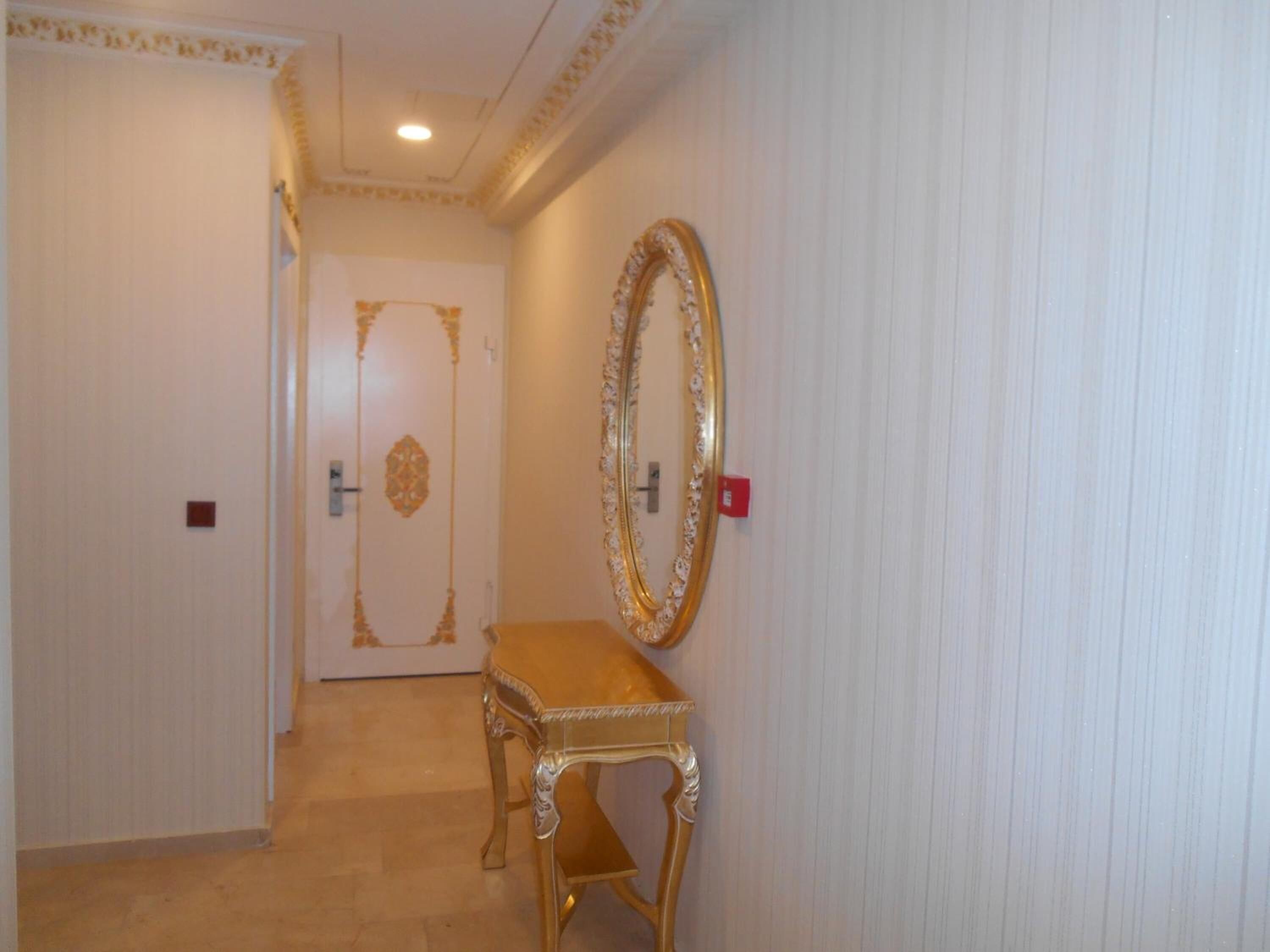 A hallway with a door, a bench, and a large mirror on the wall.