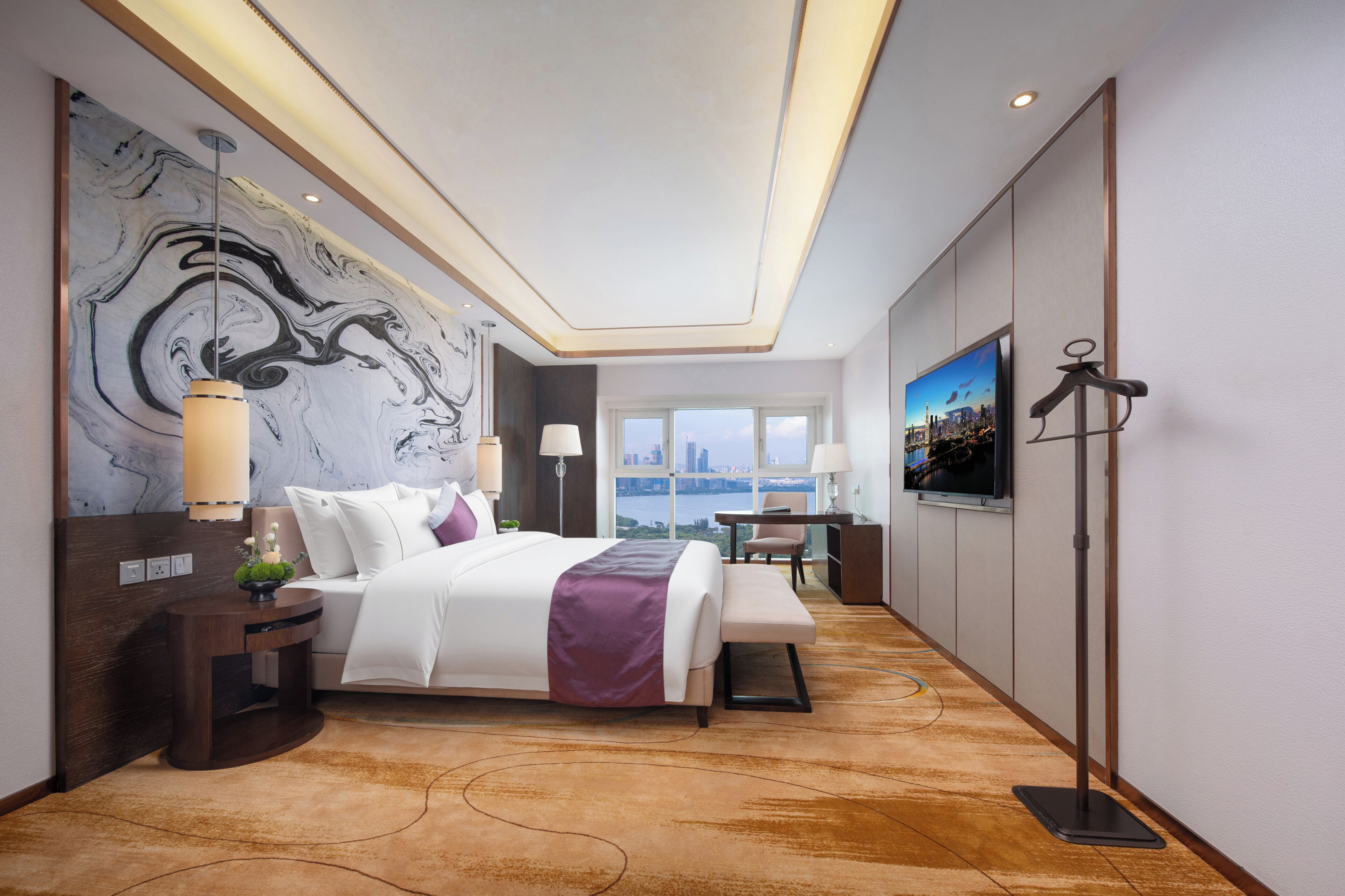 Camera d'hotel moderna con un letto grande, una scrivania, una televisione e vista sulla città.