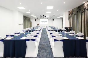 A conference room with rows of tables, chairs, and a projector screen. - Hisoar Hotel Shenzhen (Shenzhen)
