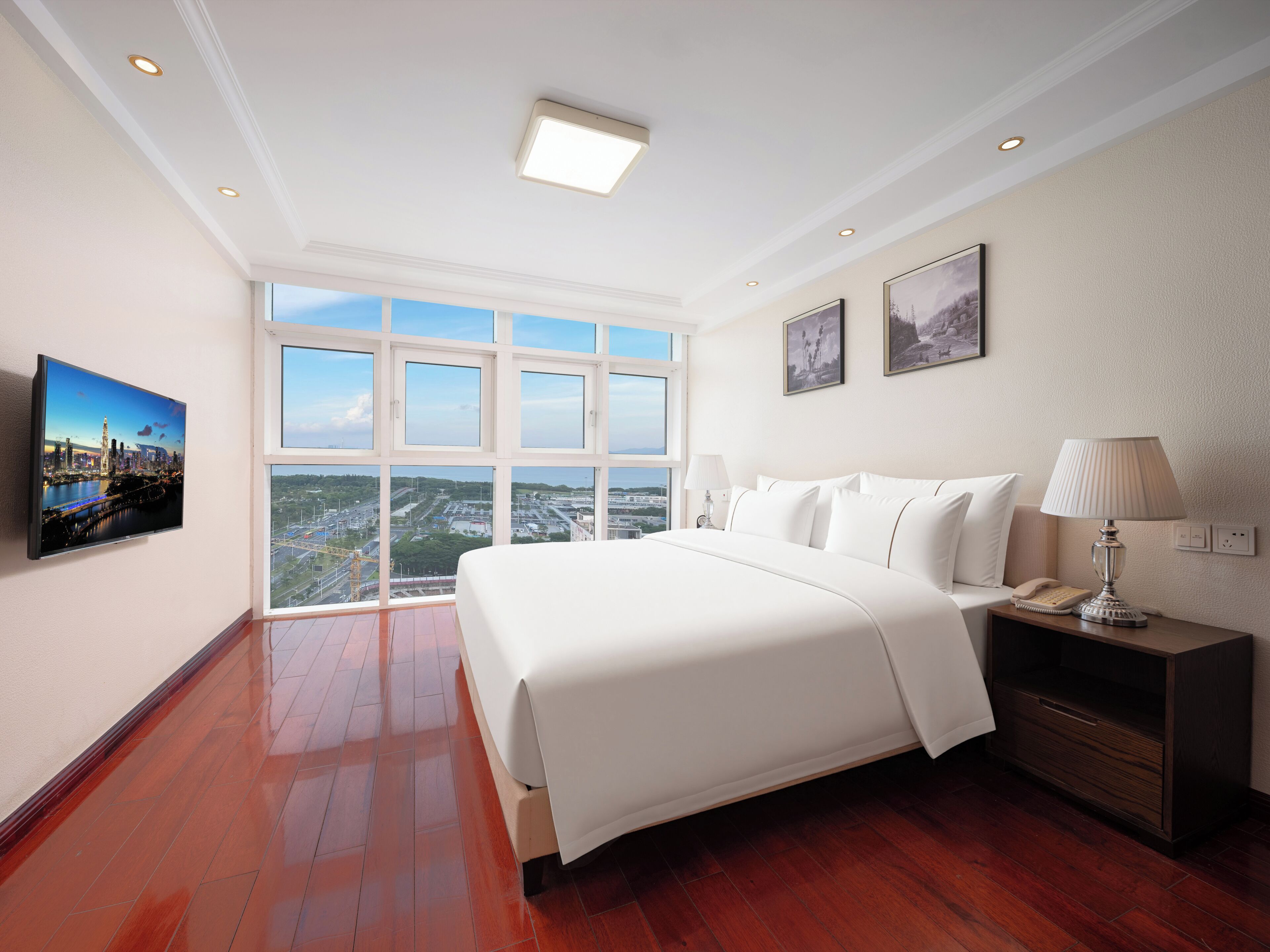 Habitación de hotel con una cama grande, una mesita de noche, una lámpara y un televisor en la pared.