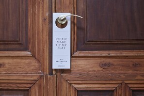 A wooden door with a sign that reads "PLEASE MAKE UP MY FLAT 60 BALCONIES". - 60 Balconies Design (Madrid)