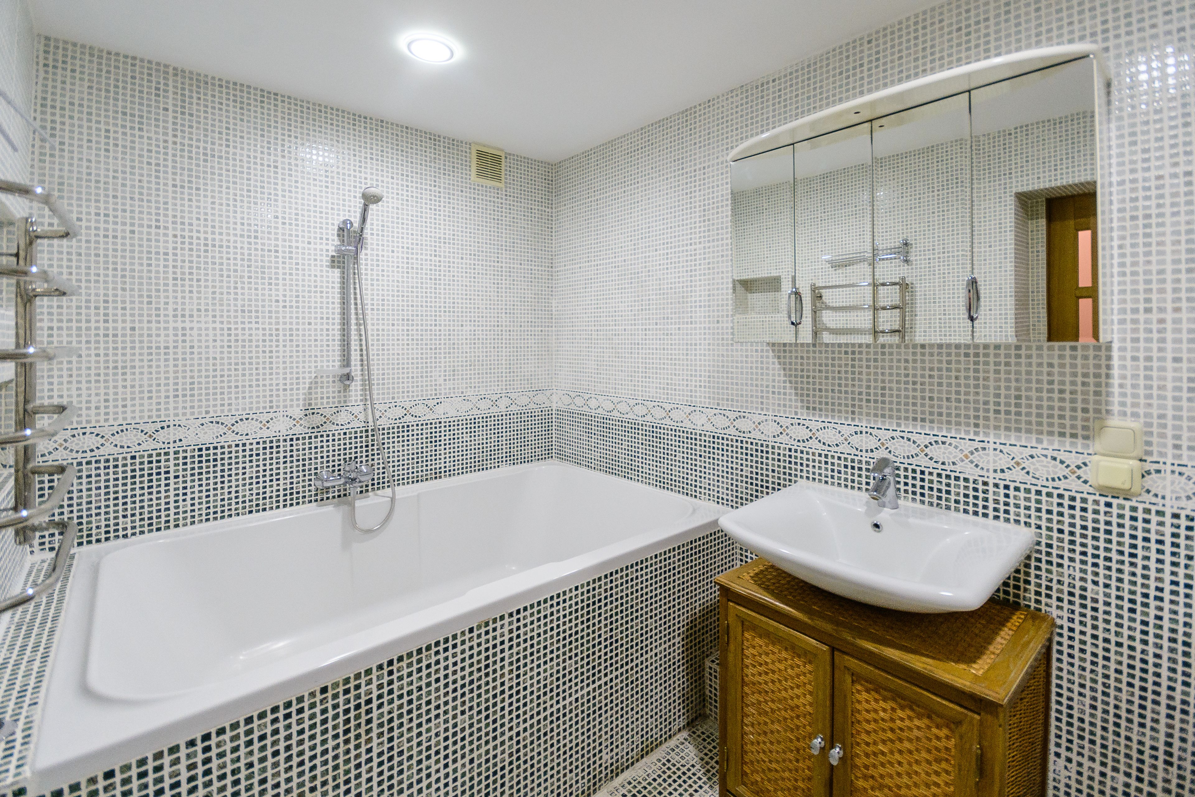 Un baño con una bañera blanca, un lavamanos y un espejo sobre él.