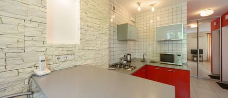Una cocina moderna con pared de piedra, armarios rojos y una isla grande.