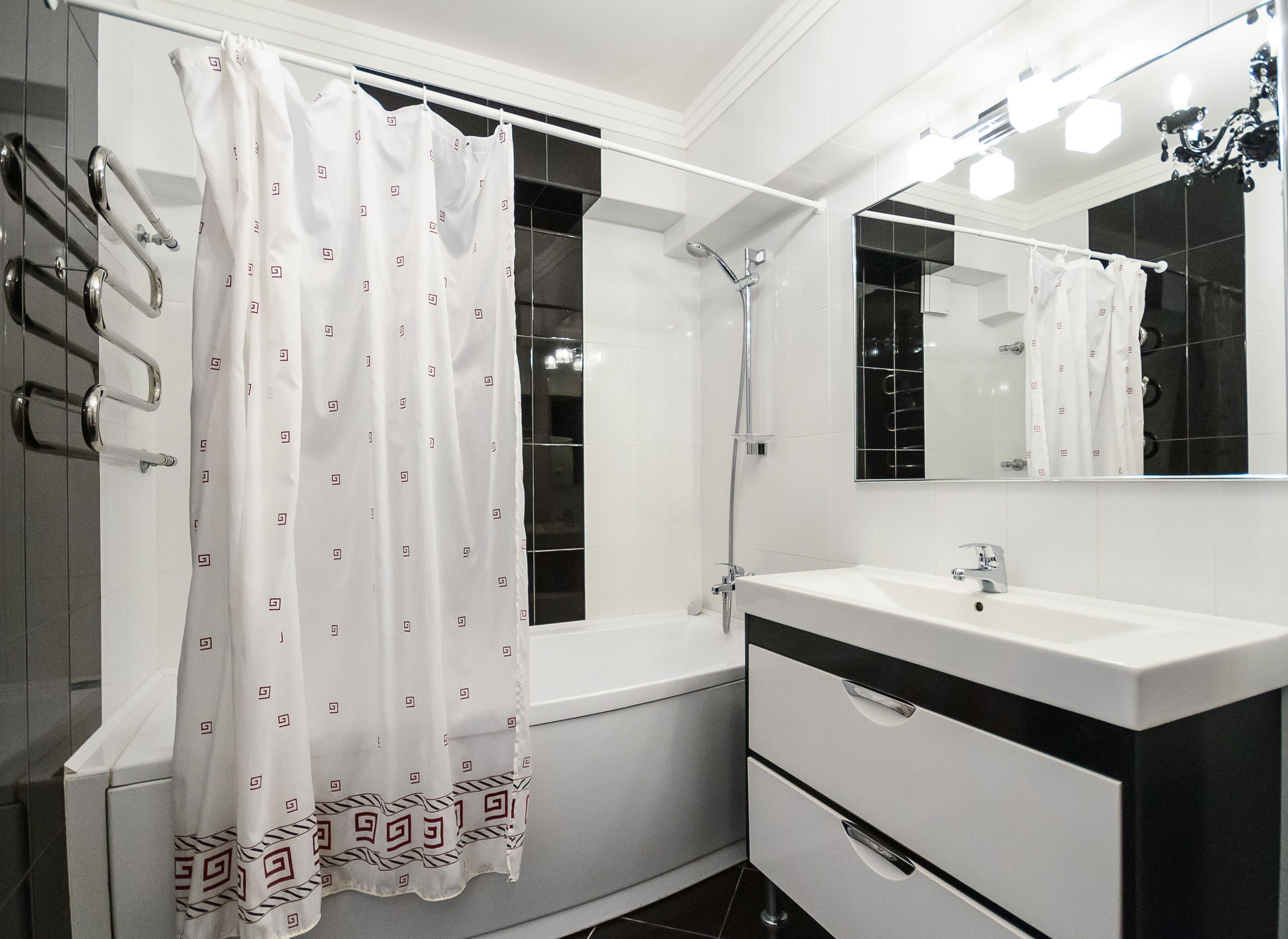 Un bagno moderno con una vasca da bagno, una doccia, un lavabo con specchio e un water.