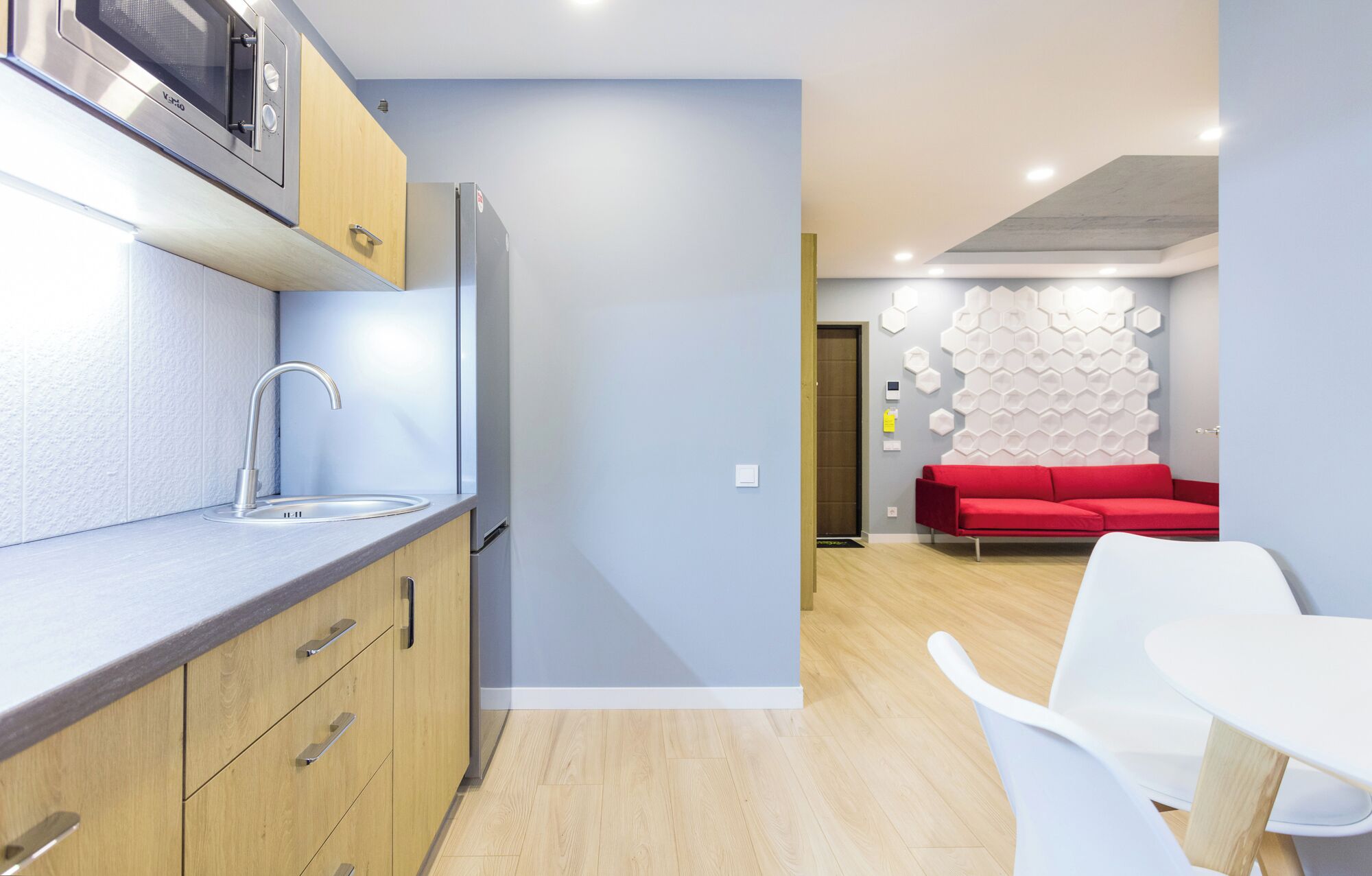 Una cocina moderna con microondas integrado, refrigerador de acero inoxidable y armarios de madera.