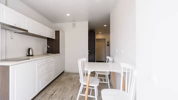 Una cocina moderna con armarios blancos, encimera de madera y un comedor con sillas y mesa blancos.
