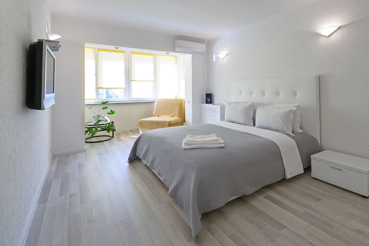 A modern bedroom with a bed, bedside tables, a chair, and a window.