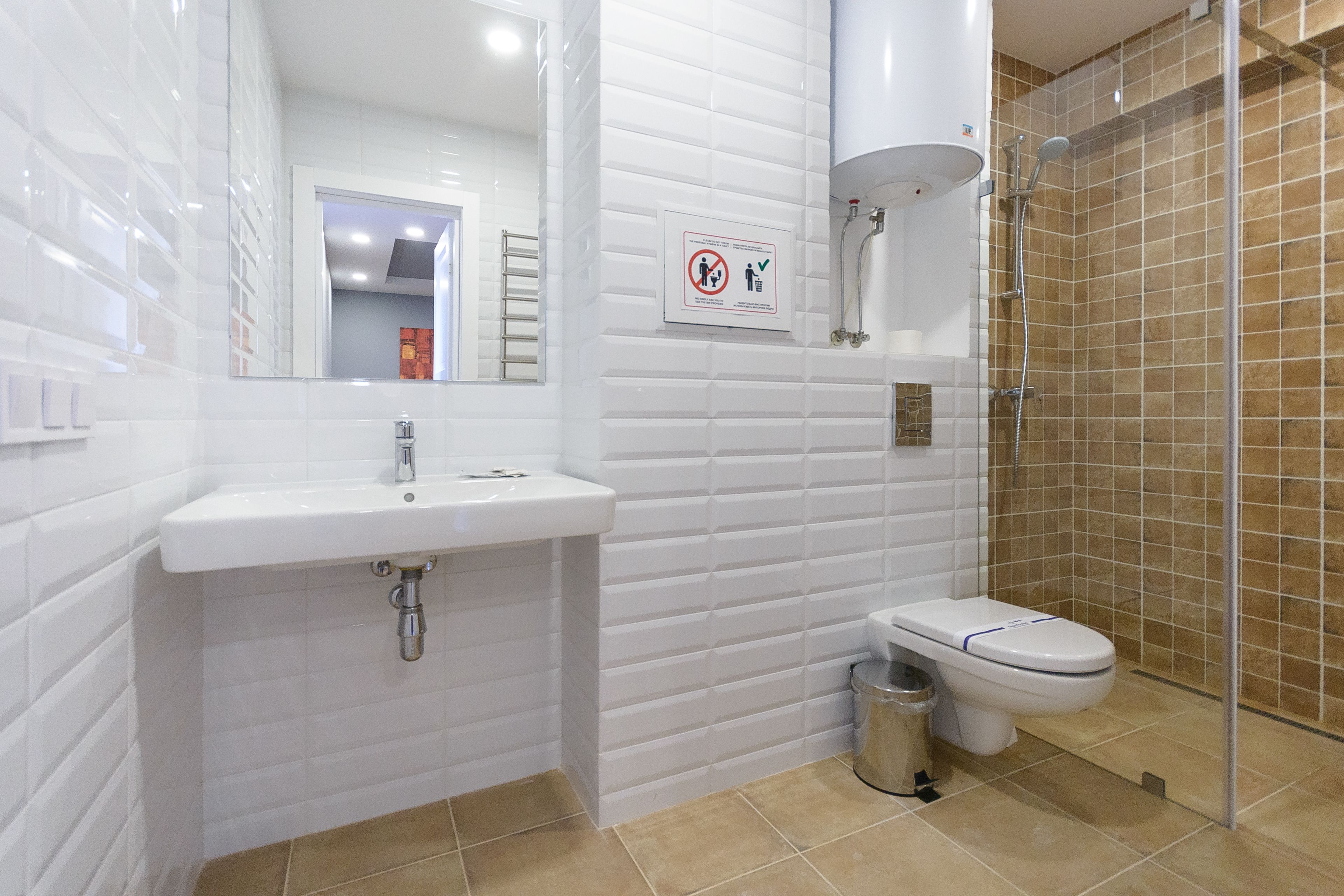 A modern bathroom with a white sink, toilet, and glass shower enclosure.