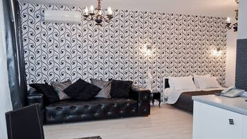 Una sala de estar moderna con un sofá de cuero negro, un escritorio blanco y un papel tapiz estampado.