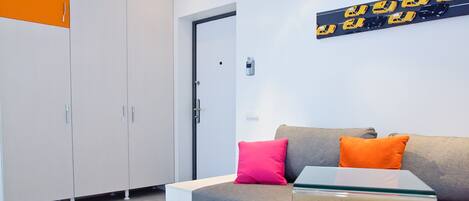 A modern room with a grey sofa, a glass coffee table, and a white wardrobe.