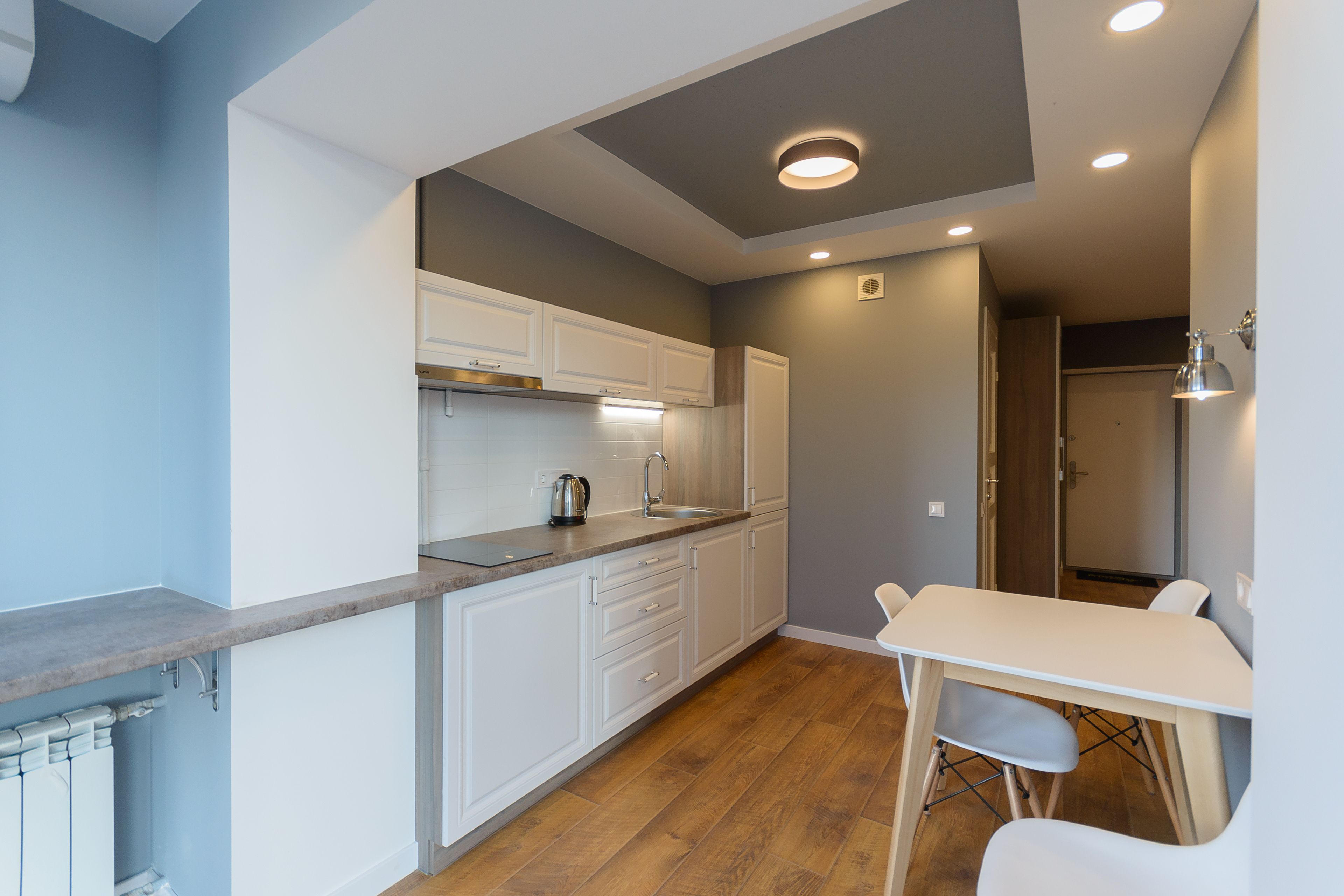 Een moderne keuken met witte kasten, een houten aanrecht en een eethoek met een witte tafel en stoelen.