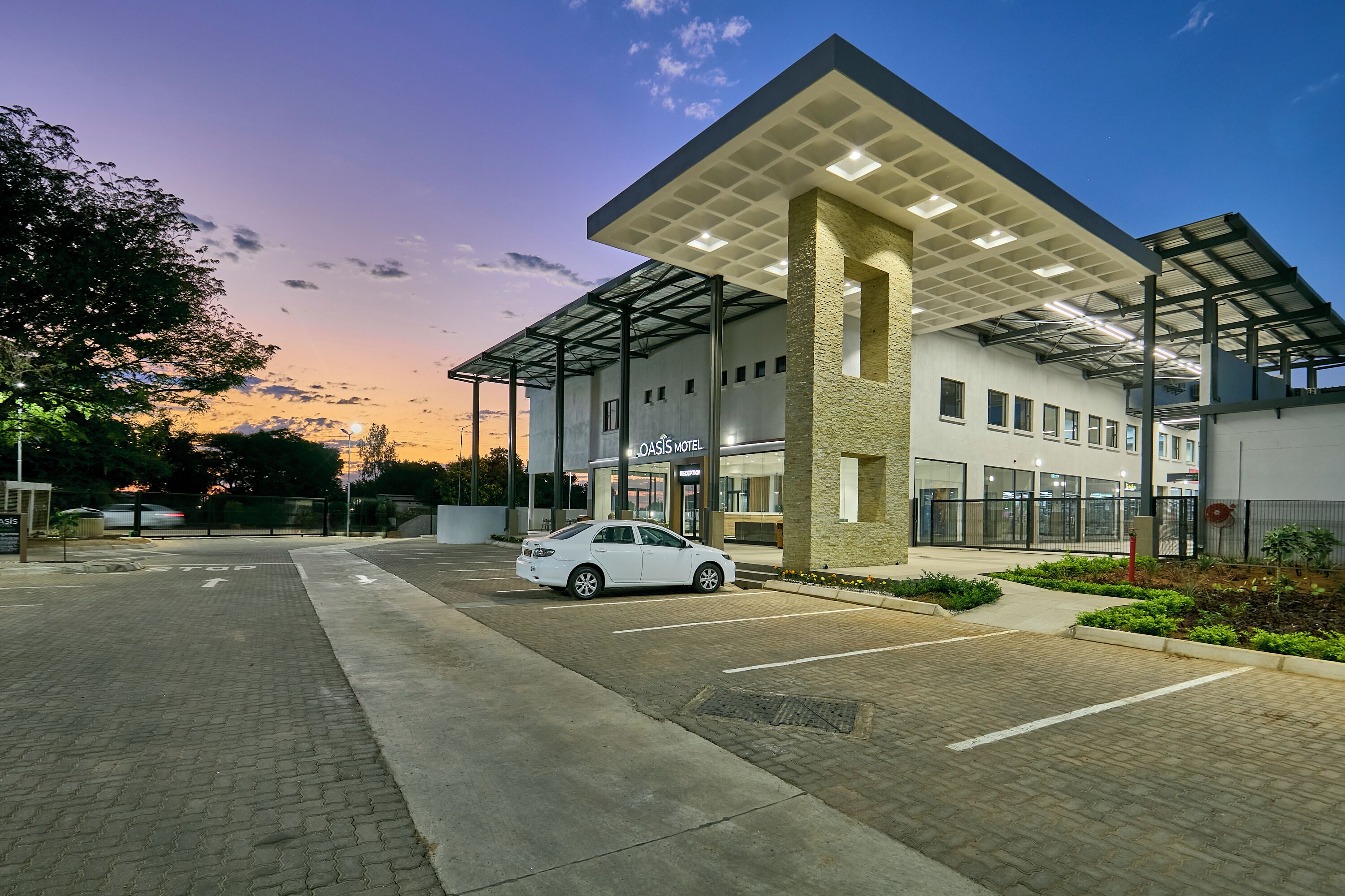 A modern hotel with a covered parking area and a white car parked in front.