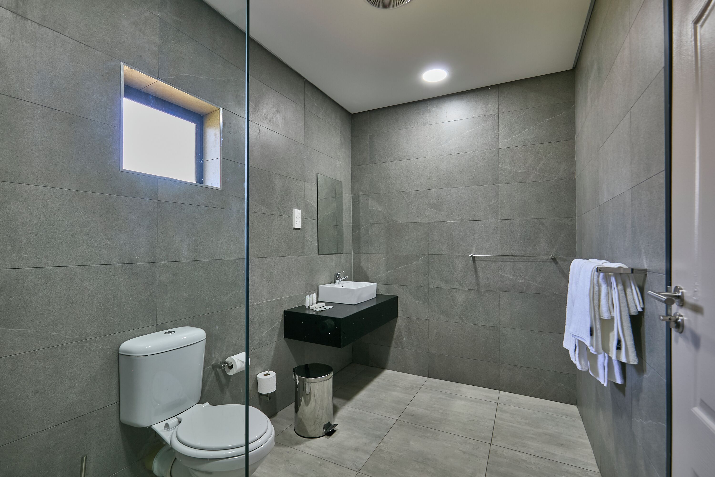 Un baño moderno con inodoro, lavabo y zona de ducha.