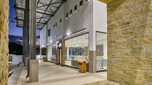 A modern hotel entrance with a reception desk, glass doors, and a stone facade.