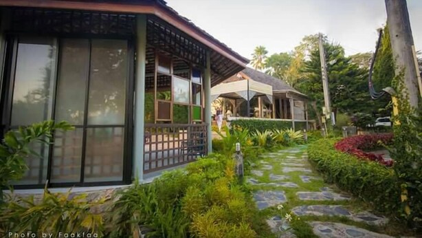 A house with a covered porch, a stone pathway, and lush greenery. - Season Namkorn Resort (Chiang Rai)