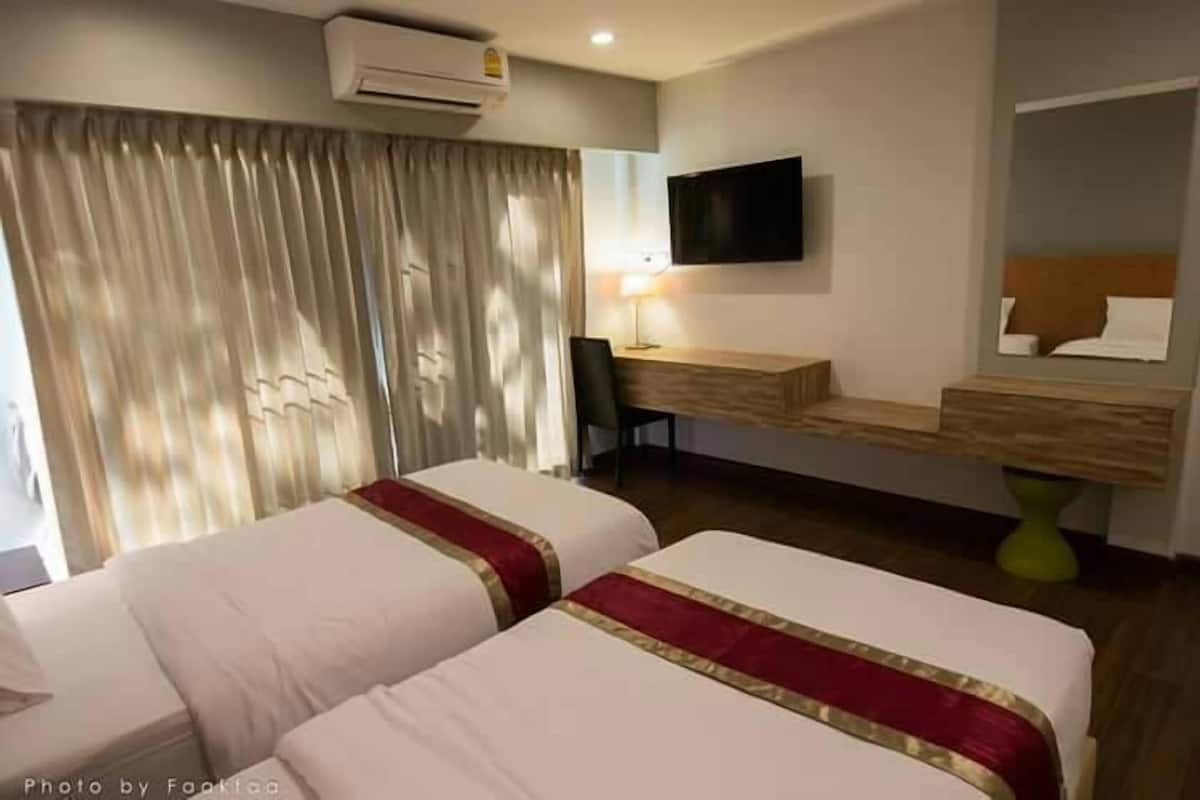 A hotel room with two beds, a desk, a chair, a TV, and a mirror.