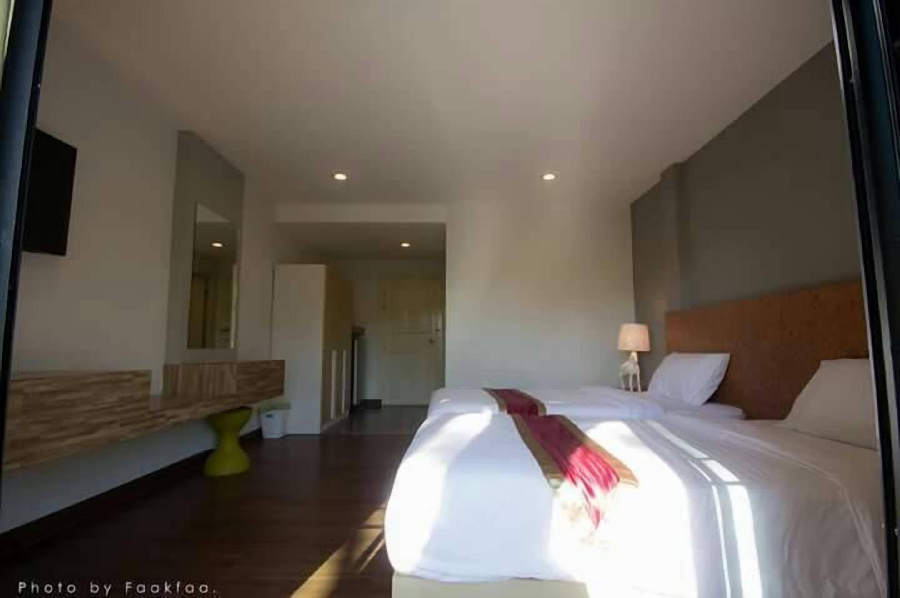 Una habitación de hotel con una cama grande, una mesita de noche, un espejo y otra mesita auxiliar.
