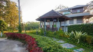A two-story building with a covered porch and a garden in front. - Season Namkorn Resort (Chiang Rai)