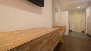 A hallway with a wooden bench, a mounted television, and a door leading to another room. - Season Namkorn Resort (Chiang Rai)