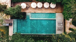 An aerial view of a swimming pool with a wooden deck, surrounded by greenery and umbrellas. - Flora Creek Resort & Garden Chiang Mai (Chiang Mai)