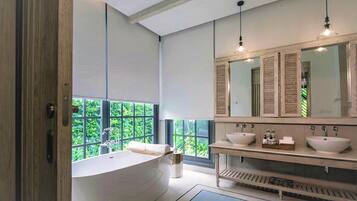 Un baño moderno con una bañera independiente, dos lavamanos y un espejo grande.