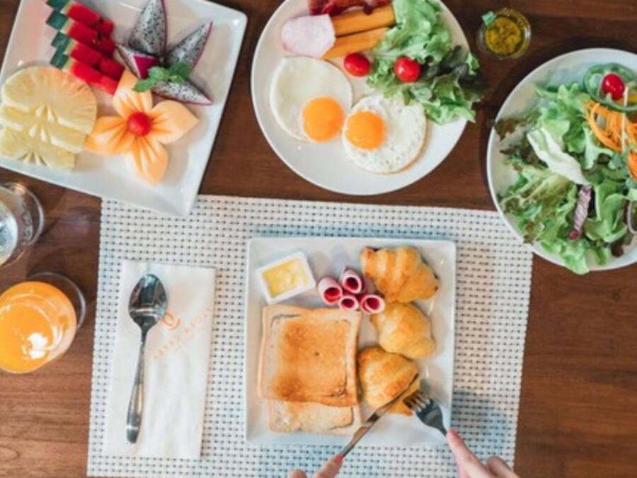 Una mesa de desayuno con platos de huevos, tostadas, cruasanes y una ensalada.
