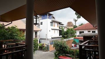 Ein Wohngebiet mit einem weißen Gebäude, einem roten Auto und einem Balkon mit Holzgeländern.