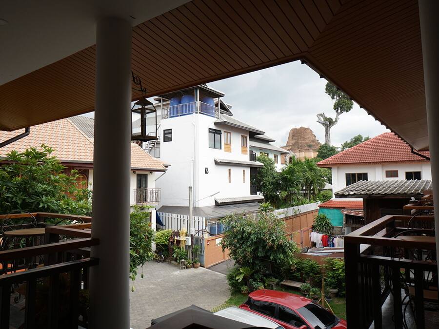 Ein Wohngebiet mit einem weißen Gebäude, einem roten Auto und einem Balkon mit Holzgeländern.