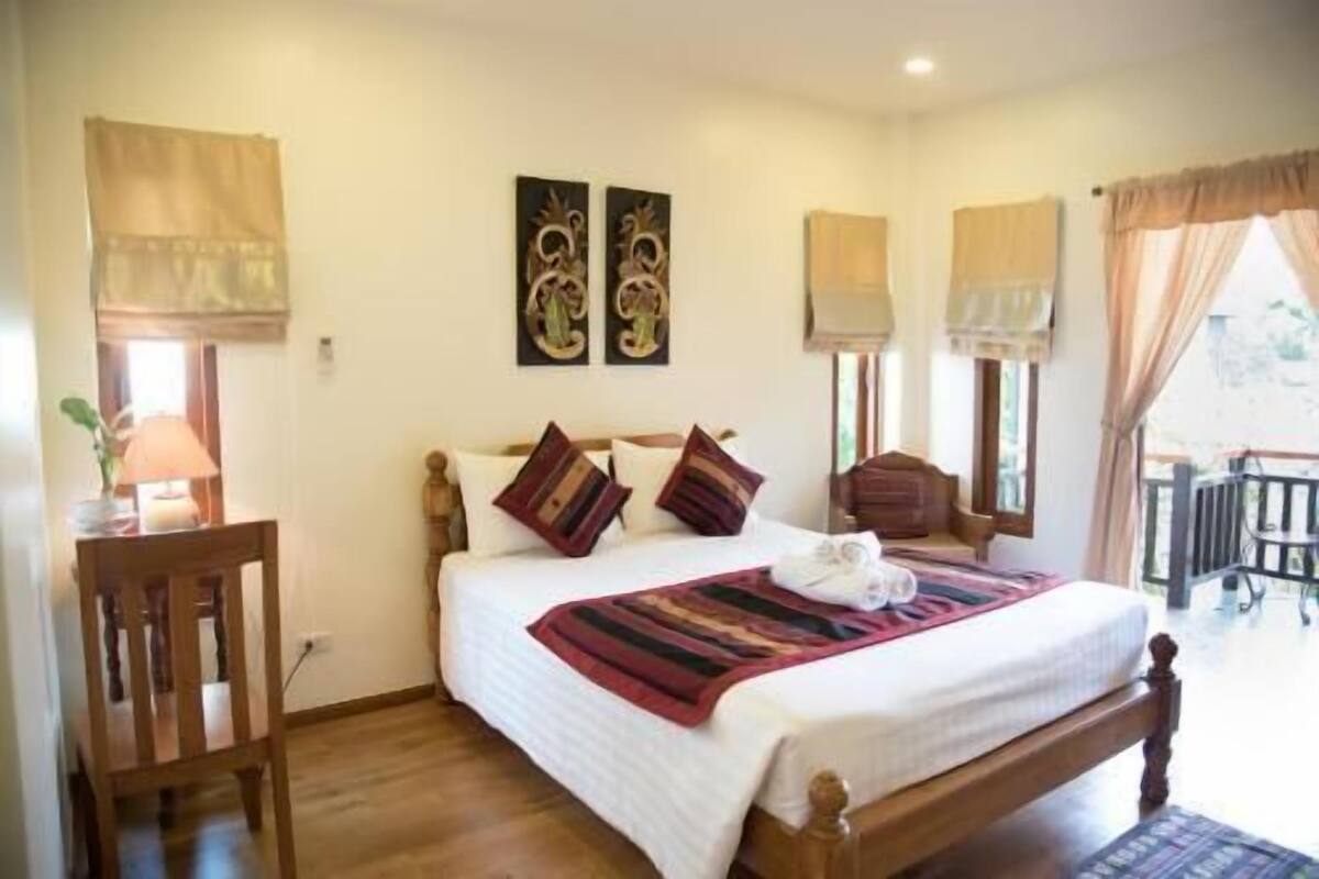 A bedroom with a wooden bed, two wall-mounted lamps, and a view of the outdoors.