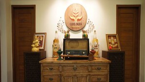 Um armário de madeira com gavetas e um rádio, ladeado por dois alto-falantes e molduras com quadros.