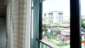 A view from a window with a metal railing, overlooking a building with multiple floors and a signboard.