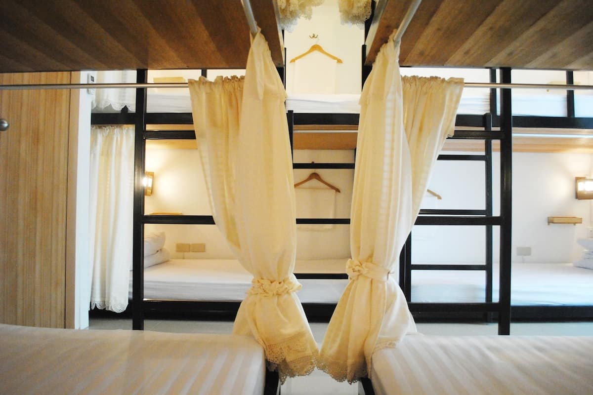Una habitación con literas, techo de madera y cortinas.