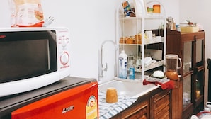 A compact kitchen with a microwave, refrigerator, and wooden cabinets.