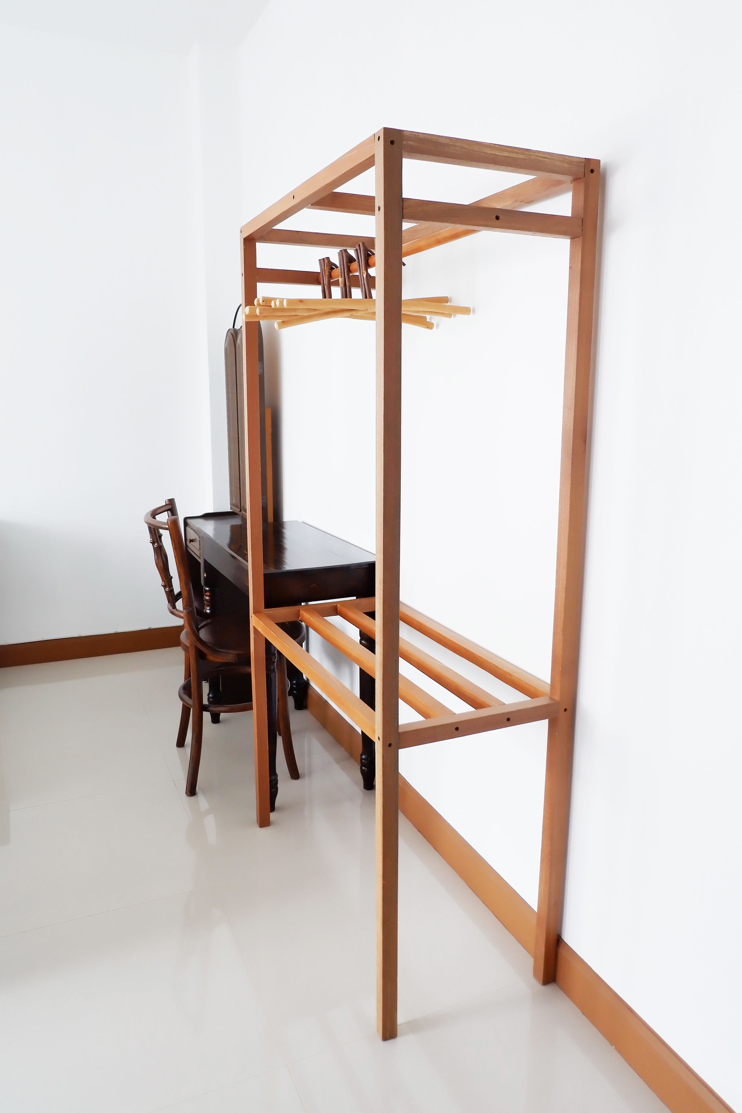 A room with a wooden desk and chair, a white wall, and a wooden frame structure.
