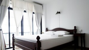 A neatly made bed with white linens, a wooden headboard, and a bedside lamp.