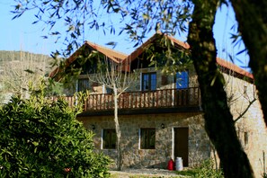 Un bâtiment en pierre doté d’un balcon en bois, de nombreuses fenêtres et d’un toit rouge.