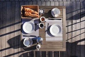 A wooden deck with a table set for a meal, including plates, cutlery, and a basket of bread. - Auberge de La Poulcière (Gerardmer)