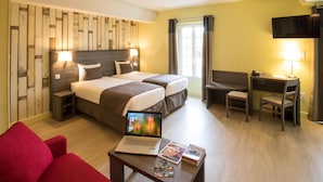 Habitación de hotel con dos camas, un escritorio, una silla, una computadora portátil y un televisor.