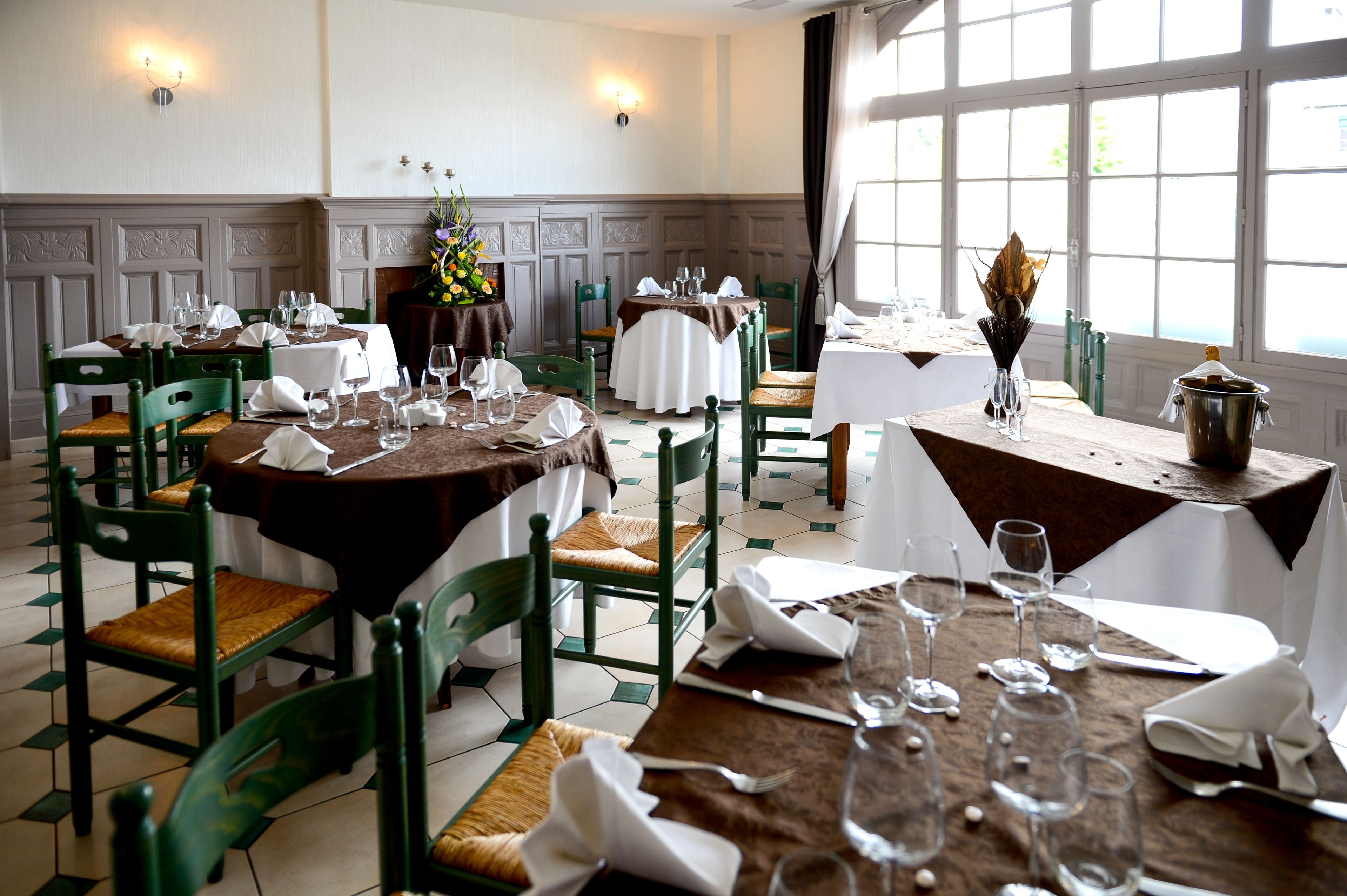 Un comedor con mesas dispuestas para comer, sillas y una ventana con cortinas.