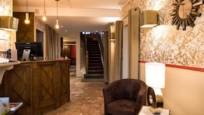 Un vestíbulo de hotel con mostrador de recepción, una escalera y un área de estar.