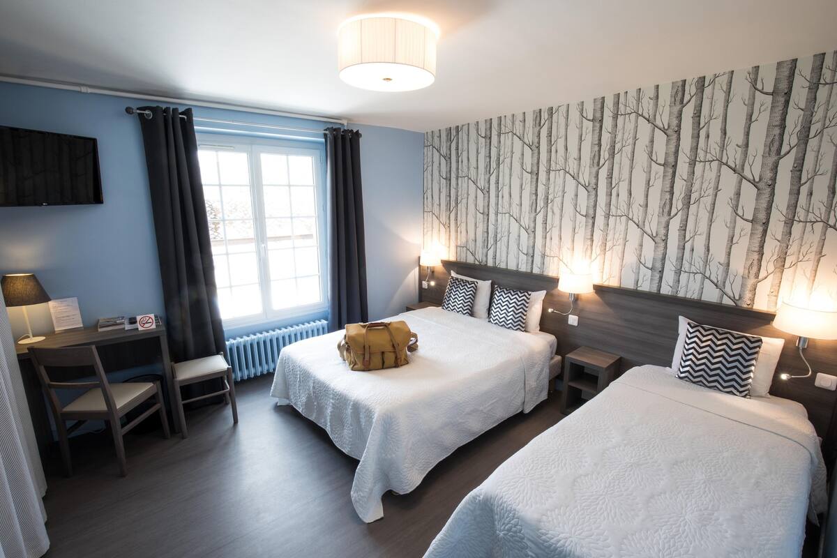 Een hotelkamer met twee bedden, een bureau en een stoel.