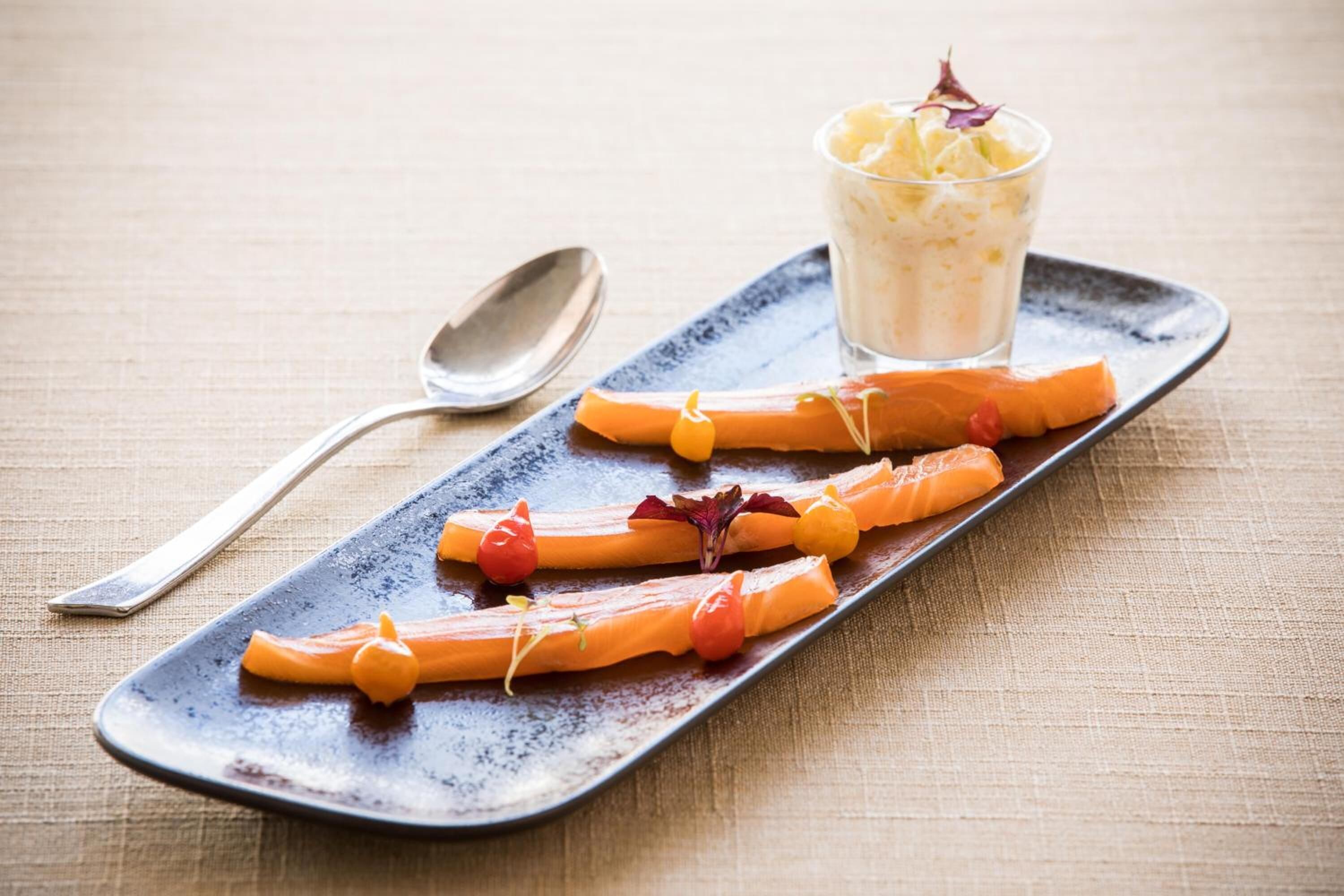 Une assiette de dessert avec des bâtonnets de carottes et un verre de crème dessert.