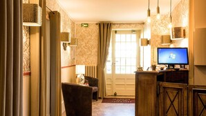 Un vestíbulo de hotel con una recepción, una pantalla de ordenador, un sofá y una puerta con ventanal.