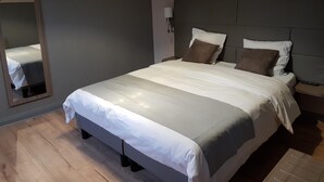 A neatly made bed with white and grey bedding, a headboard, and a bedside lamp. - Logis hôtel du château de la motte (Liessies)