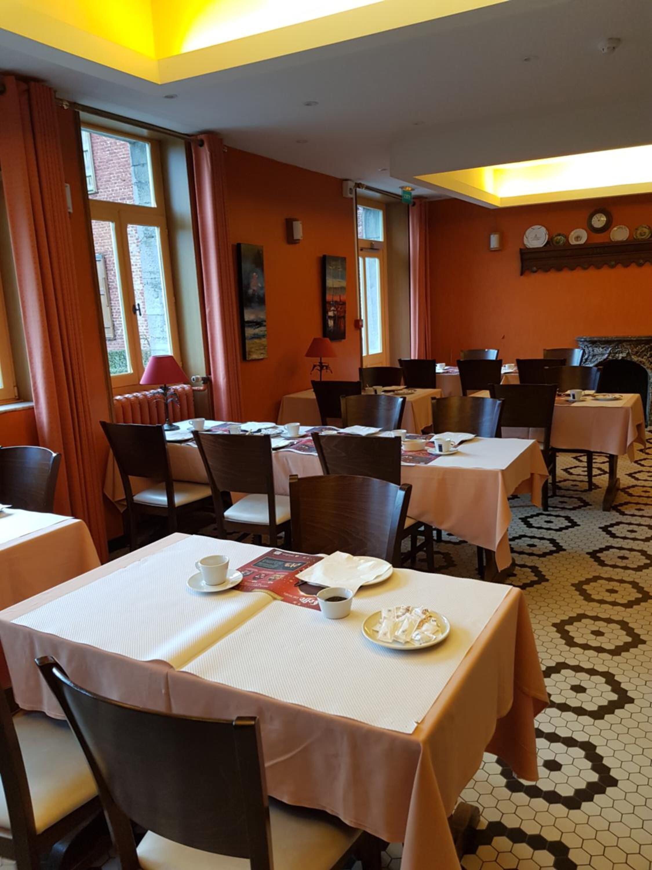 A dining area with multiple tables and chairs, a patterned floor, and a window with curtains.