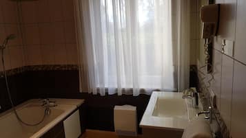 Un bany amb banyera, dutxa, vàter i un lavabo.