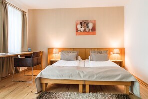 Habitación de hotel con una cama doble, dos lámparas de noche, un escritorio con una silla y un cuadro en la pared.