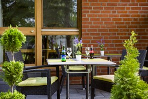Un patio al aire libre con sillas de mimbre y una mesa lista para comer.