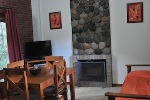 Una sala de estar con televisión, muebles de madera, una pared de piedra y una chimenea.