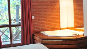 Una habitación con una bañera de madera, una ventana con cortinas y una pared de ladrillo.